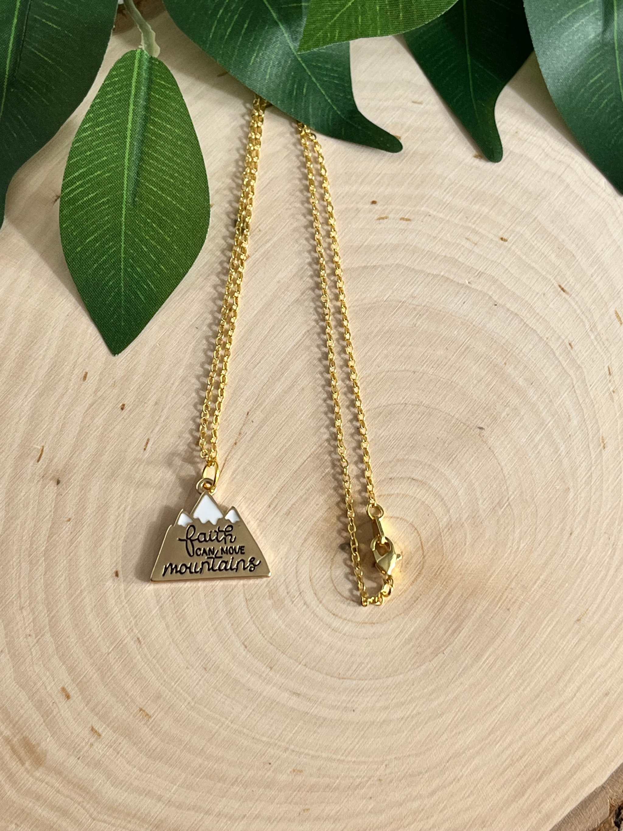 Gold chain necklace with heart pendant engraved with scripture text, close-up