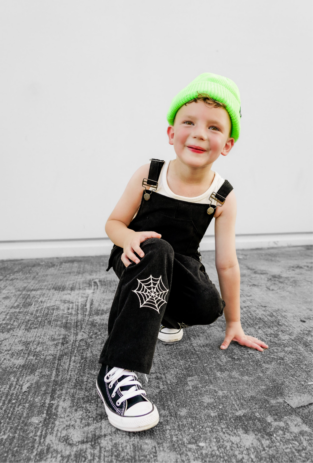 Black overalls with front straps and white spiderweb patch on one pant leg.