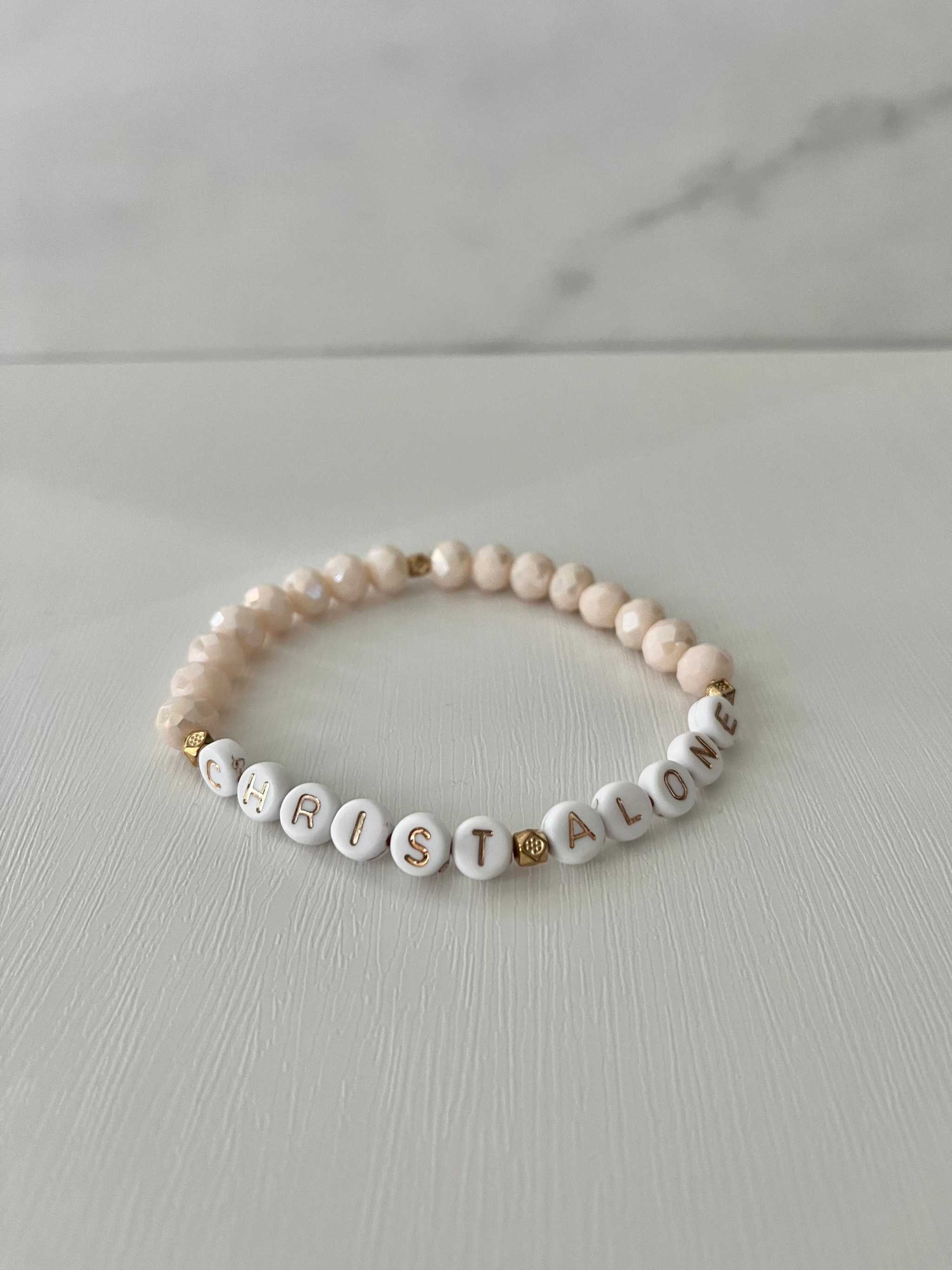 Peach-toned bead bracelet with “Christ Alone” letter beads