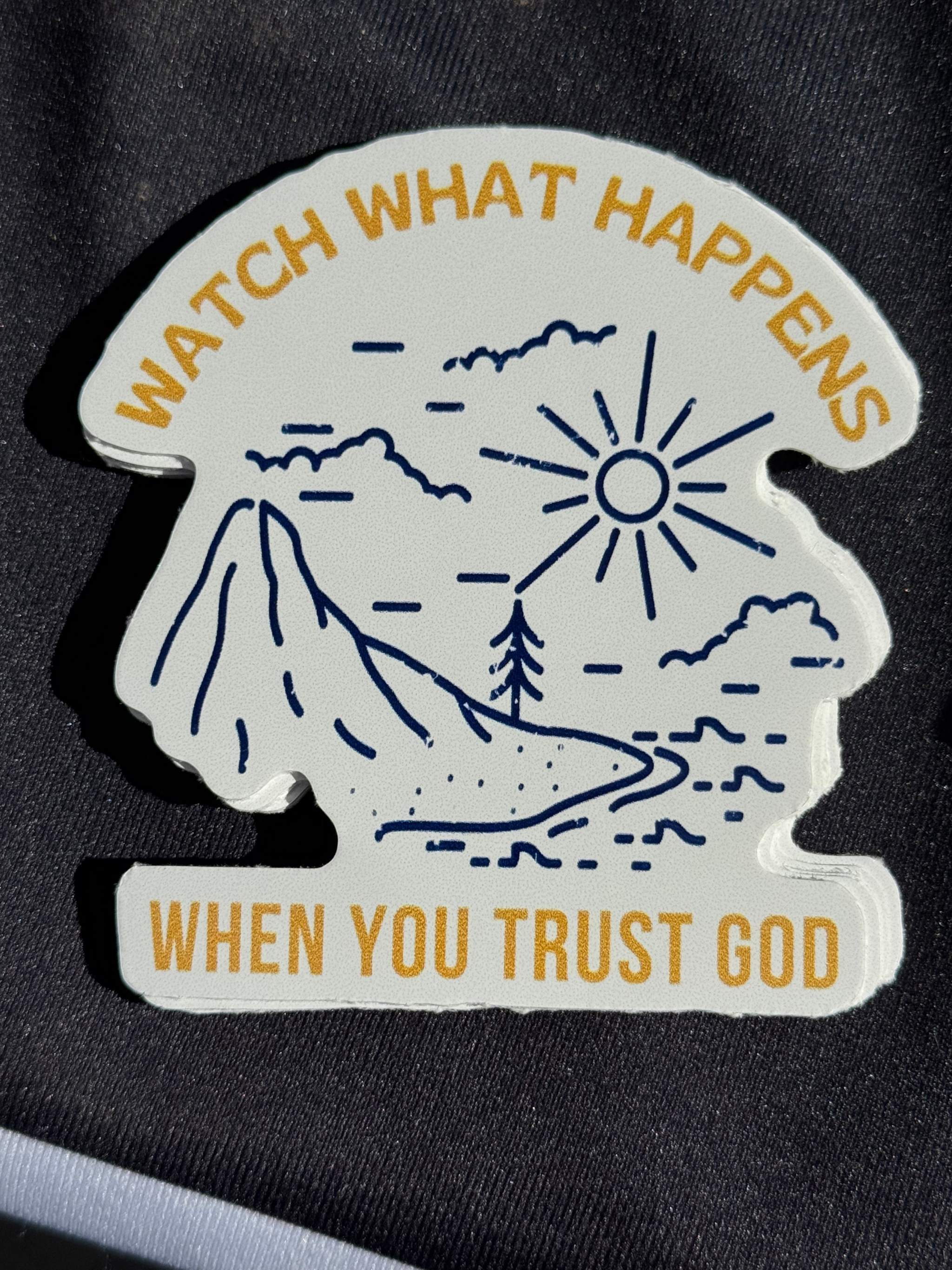 Vinyl sticker with mountains and sun, 'WATCH WHAT HAPPENS' and 'TRUST GOD' text