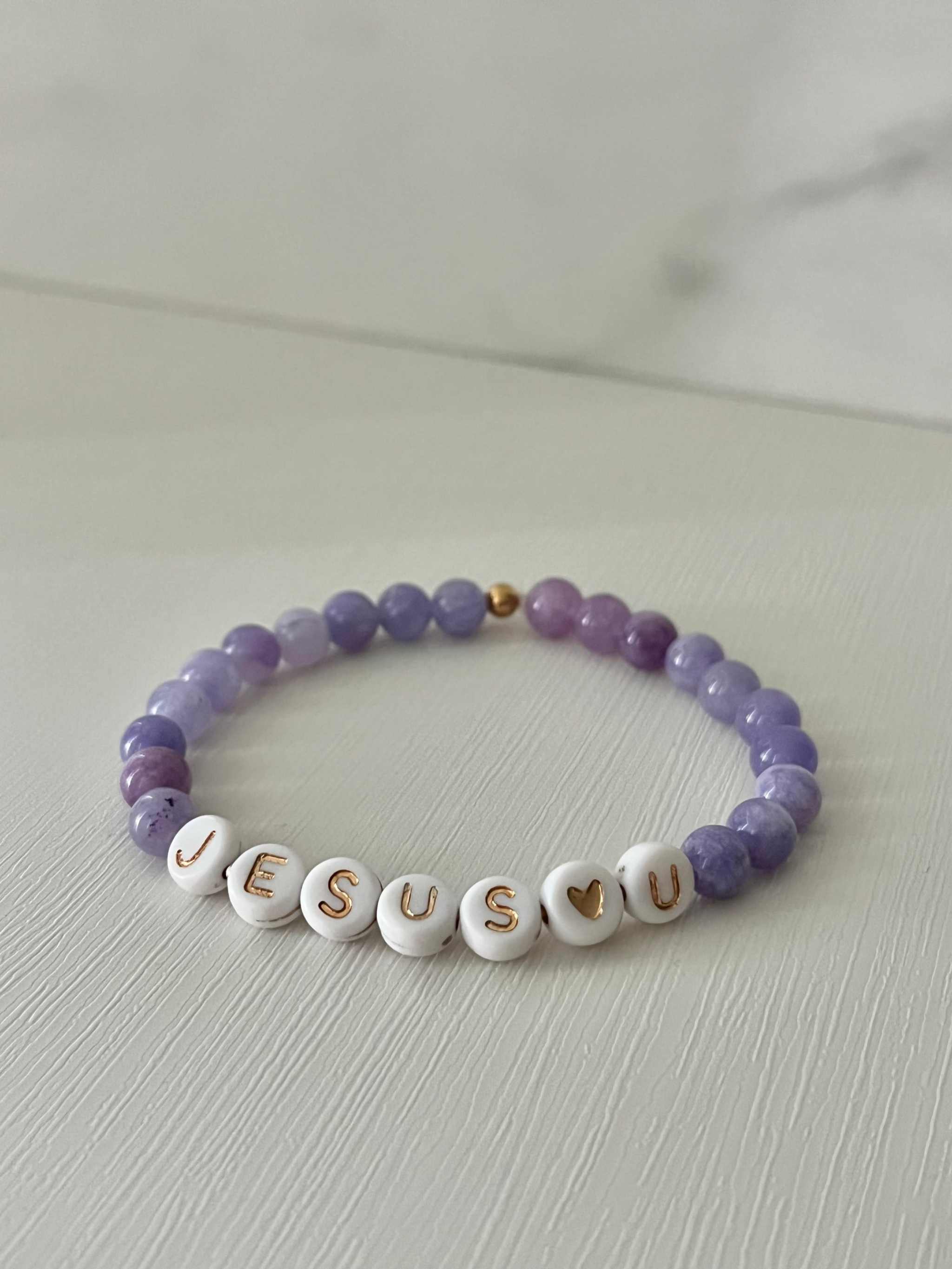 Purple beaded bracelet with white letter beads spelling "JESUS U"