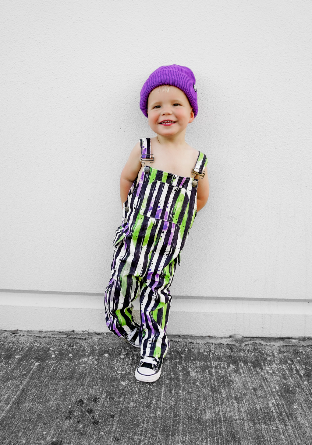 Kids striped Halloween overalls with neon green and purple pattern and adjustable straps