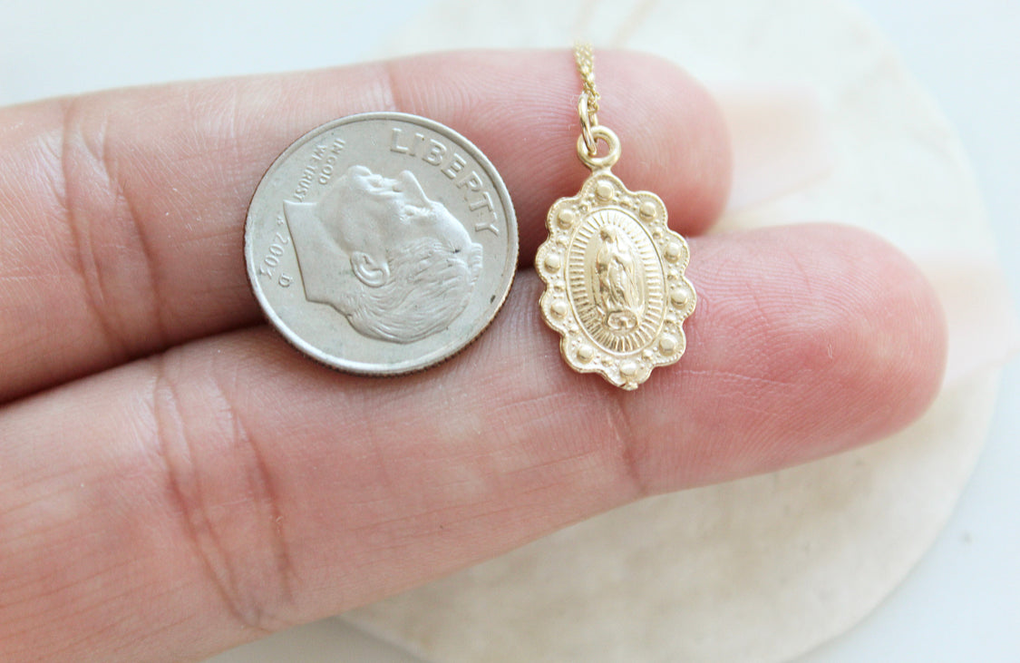 14k gold Our Lady of Guadalupe scalloped pendant side by coin for scale