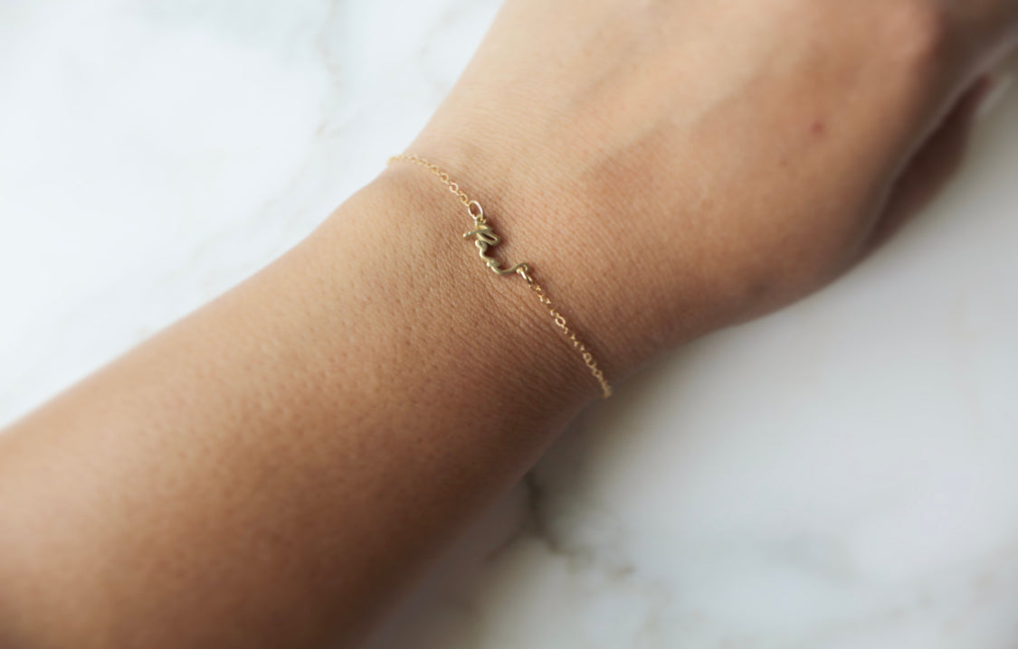 Pax bracelet close-up on wrist, delicate gold-tone chain and small charm