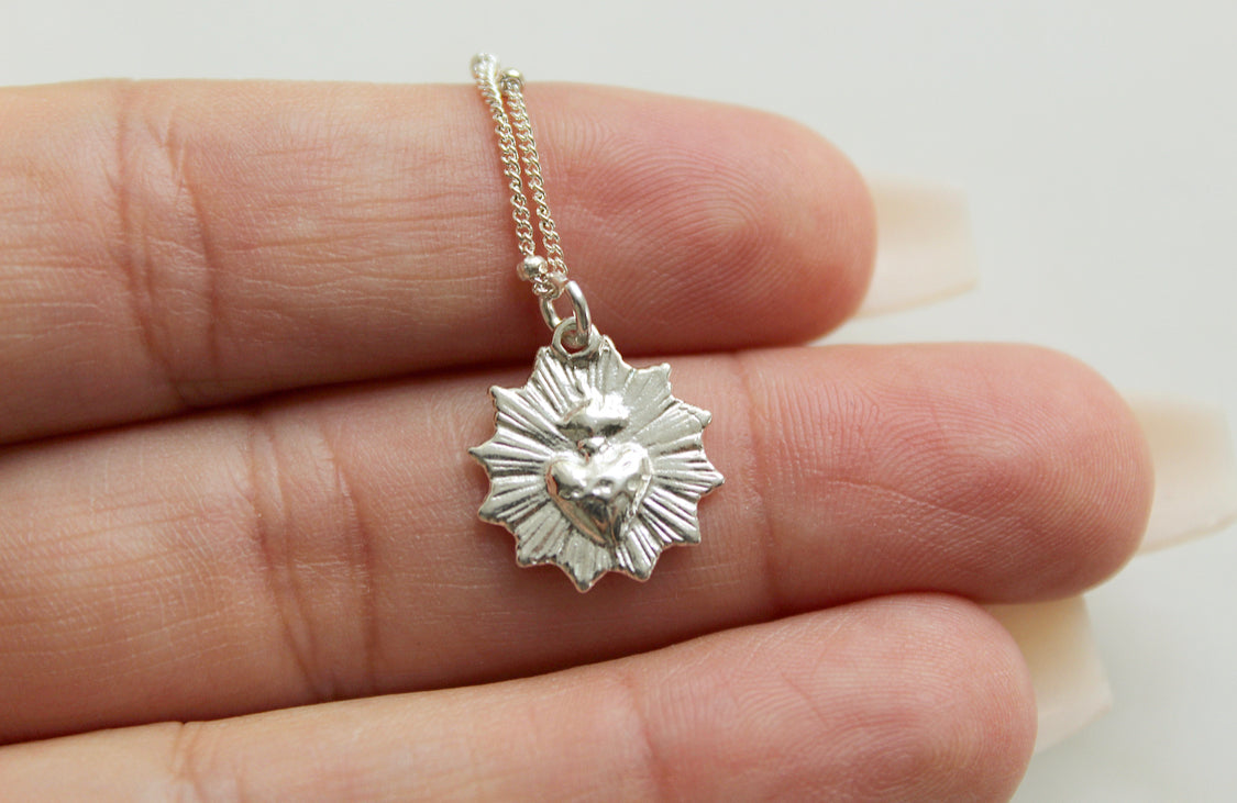 Sterling silver heart pendant with scalloped edges hanging from a delicate chain