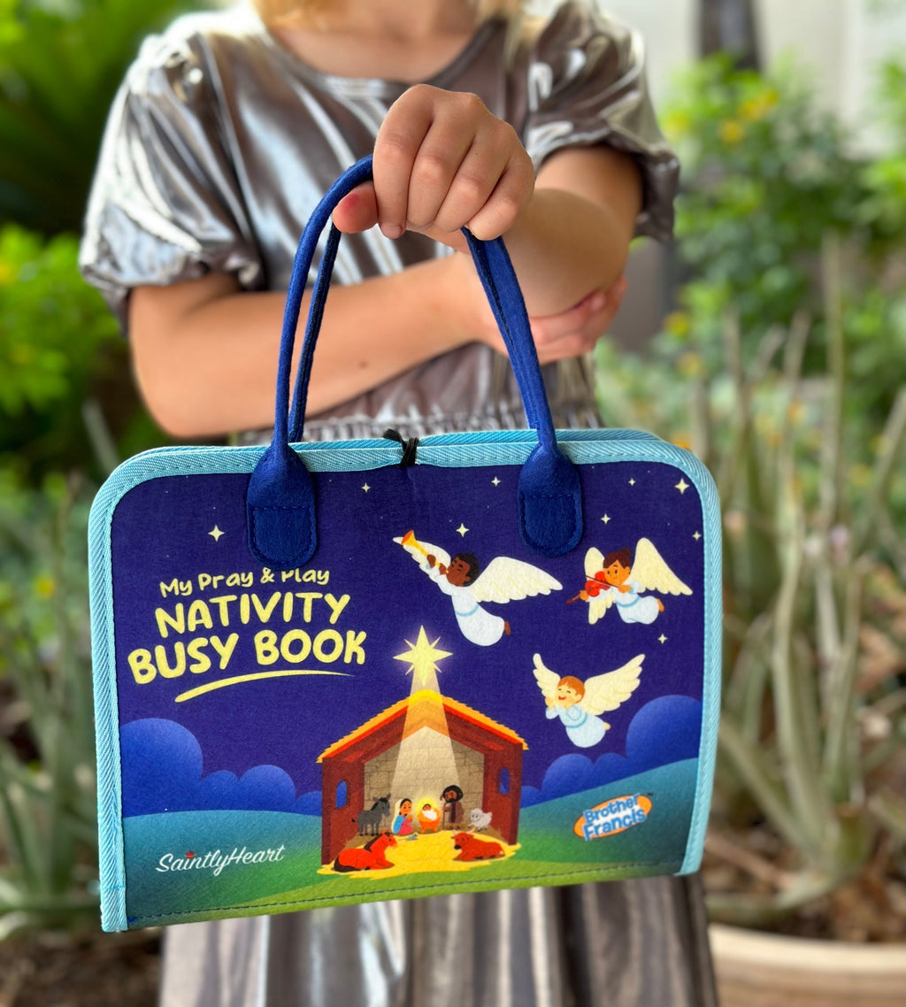 Child holding blue nativity busy book with stars and manger scene cover