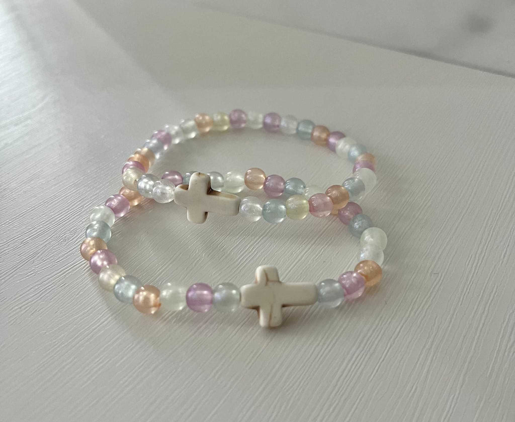 Pair of pastel bead bracelets with white cross charms, overlapping.