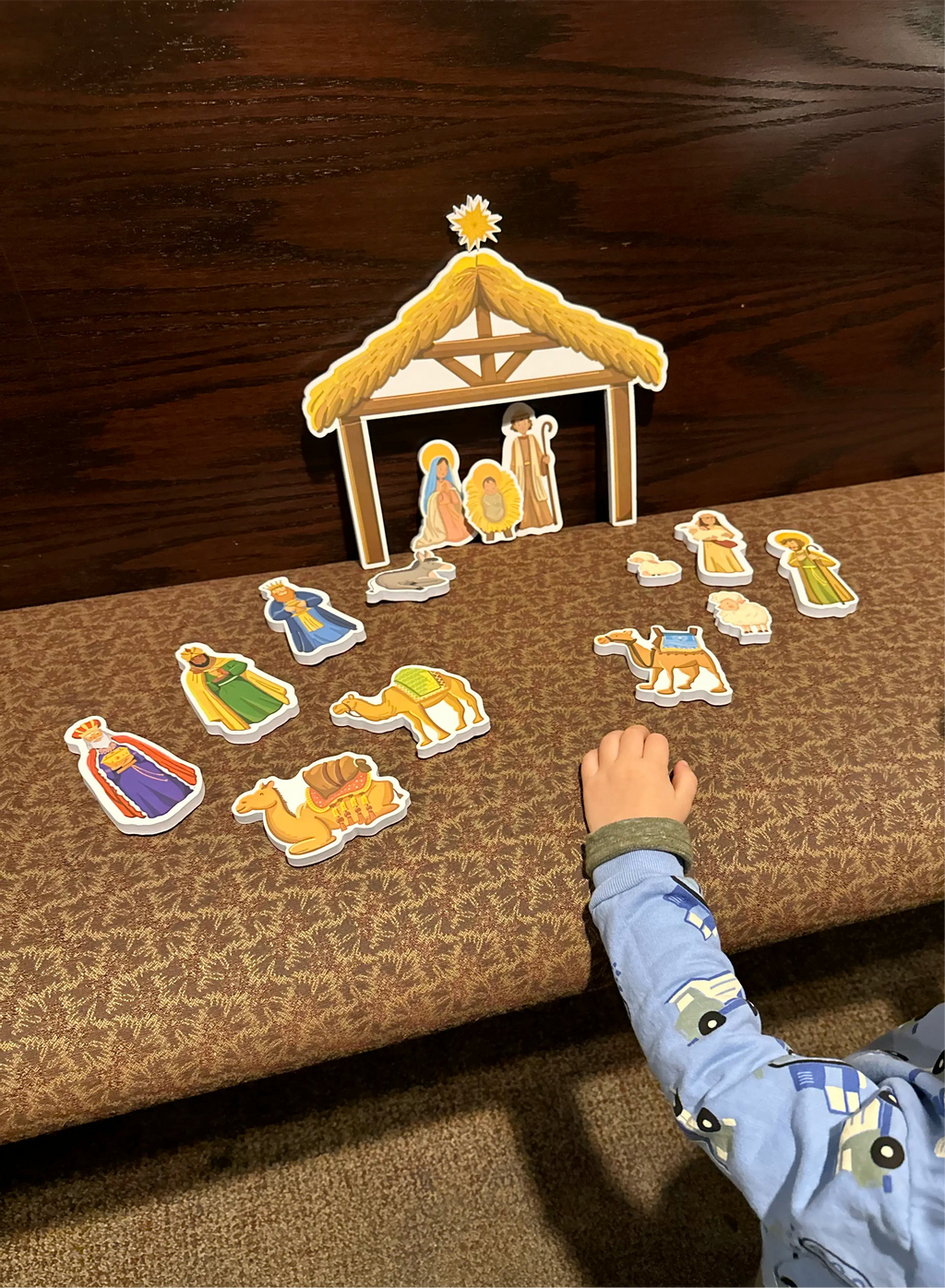 Nativity bath toy stable with animal and figure cutouts laid out on cloth