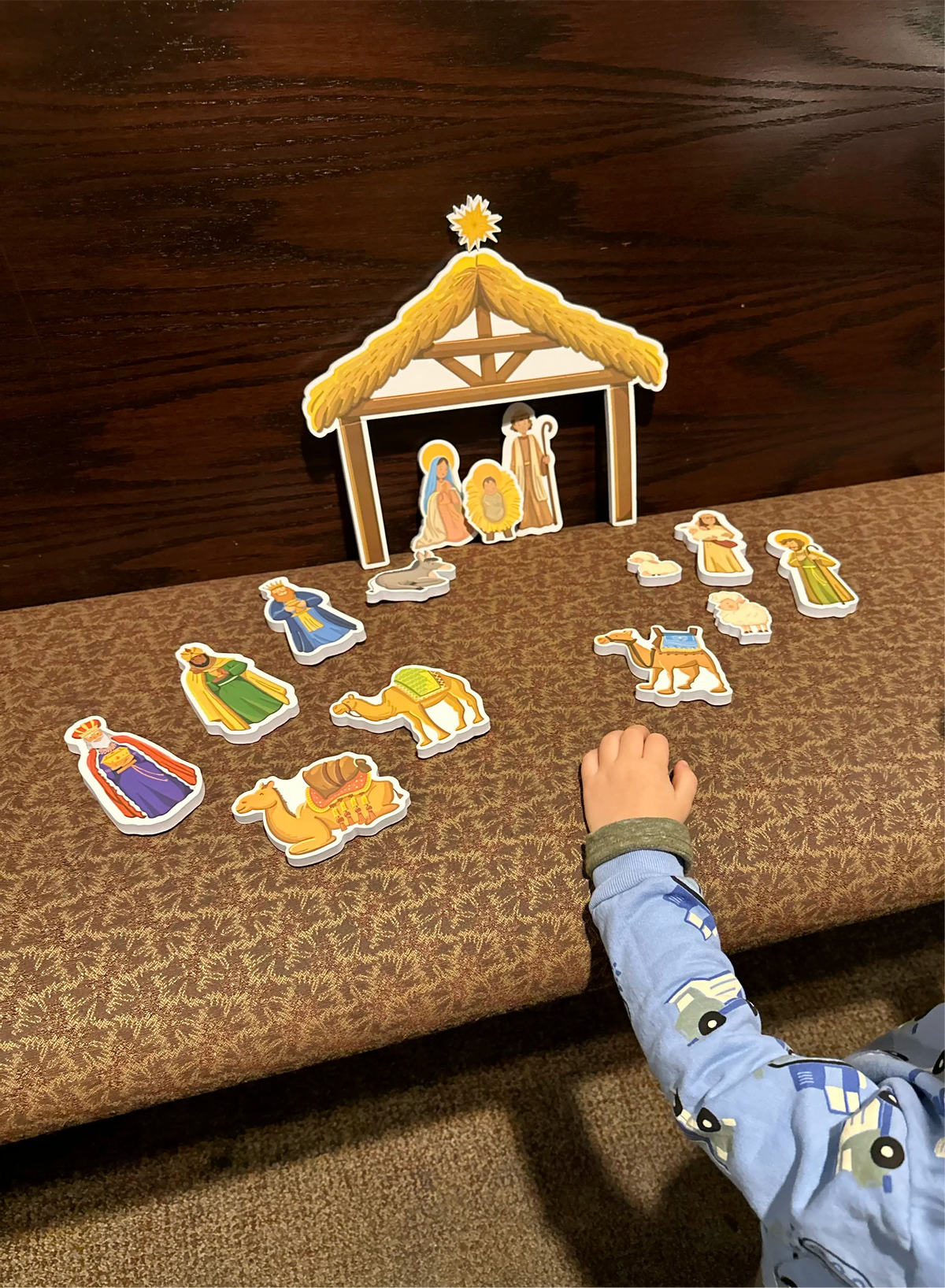 Nativity bath toy stable with animal and figure cutouts laid out on cloth