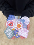 Faith-themed sticker set in hands, featuring circular badges and heart decals.