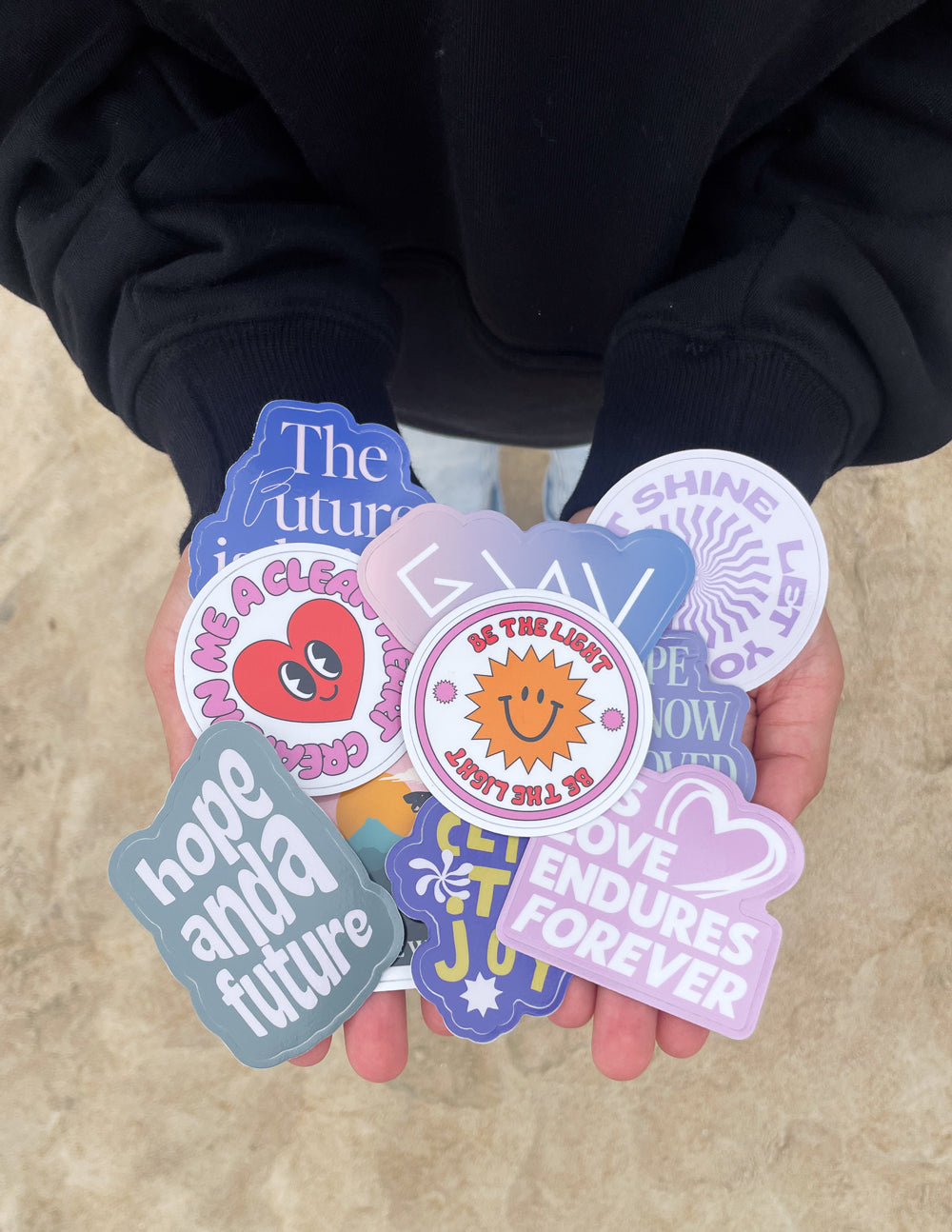 Faith-themed sticker set in hands, featuring circular badges and heart decals.