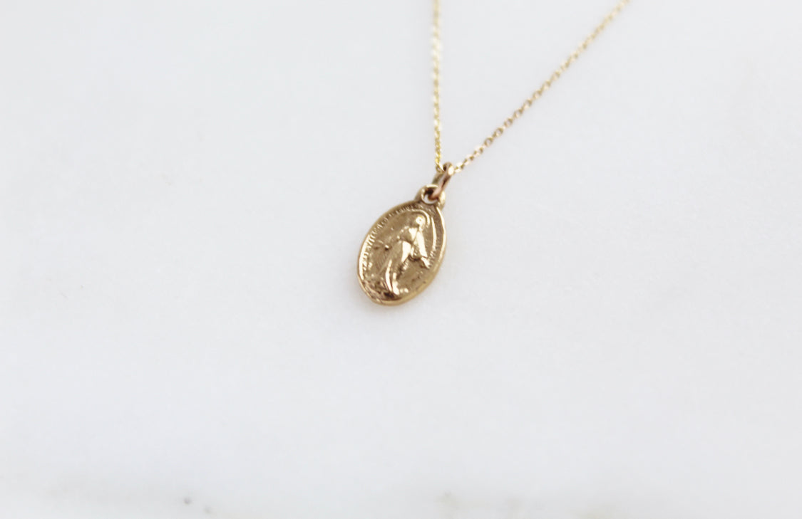 14k gold miraculous medal necklace pendant on a delicate chain, angled close-up
