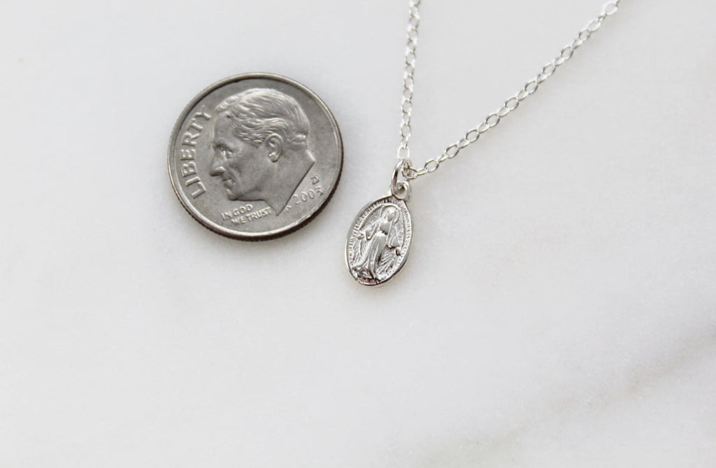 Sterling silver oval medal charm necklace shown beside a coin for scale