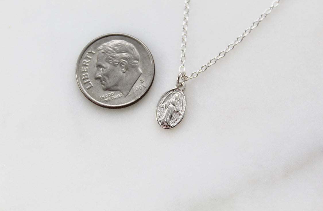 Sterling silver oval medal charm necklace shown beside a coin for scale