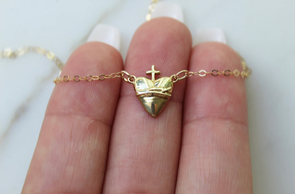 Gold-tone heart pendant necklace with cross detail on triangular charm