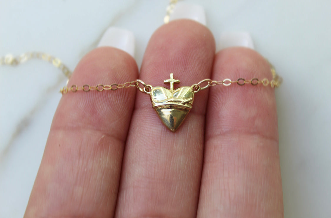 Gold-tone heart pendant necklace with cross detail on triangular charm