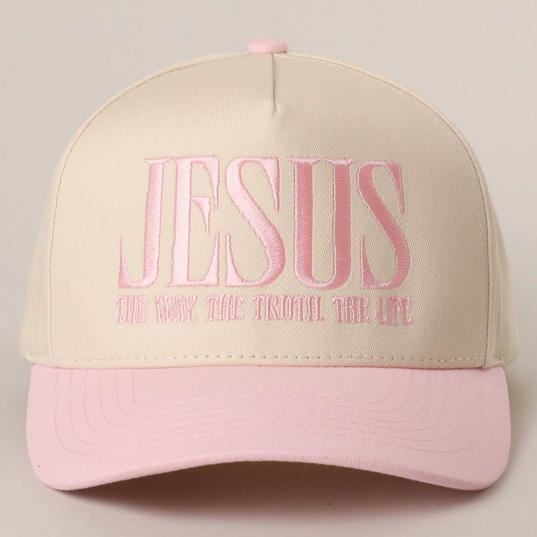Sand baseball cap with light pink brim and embroidered “JESUS” slogan on front