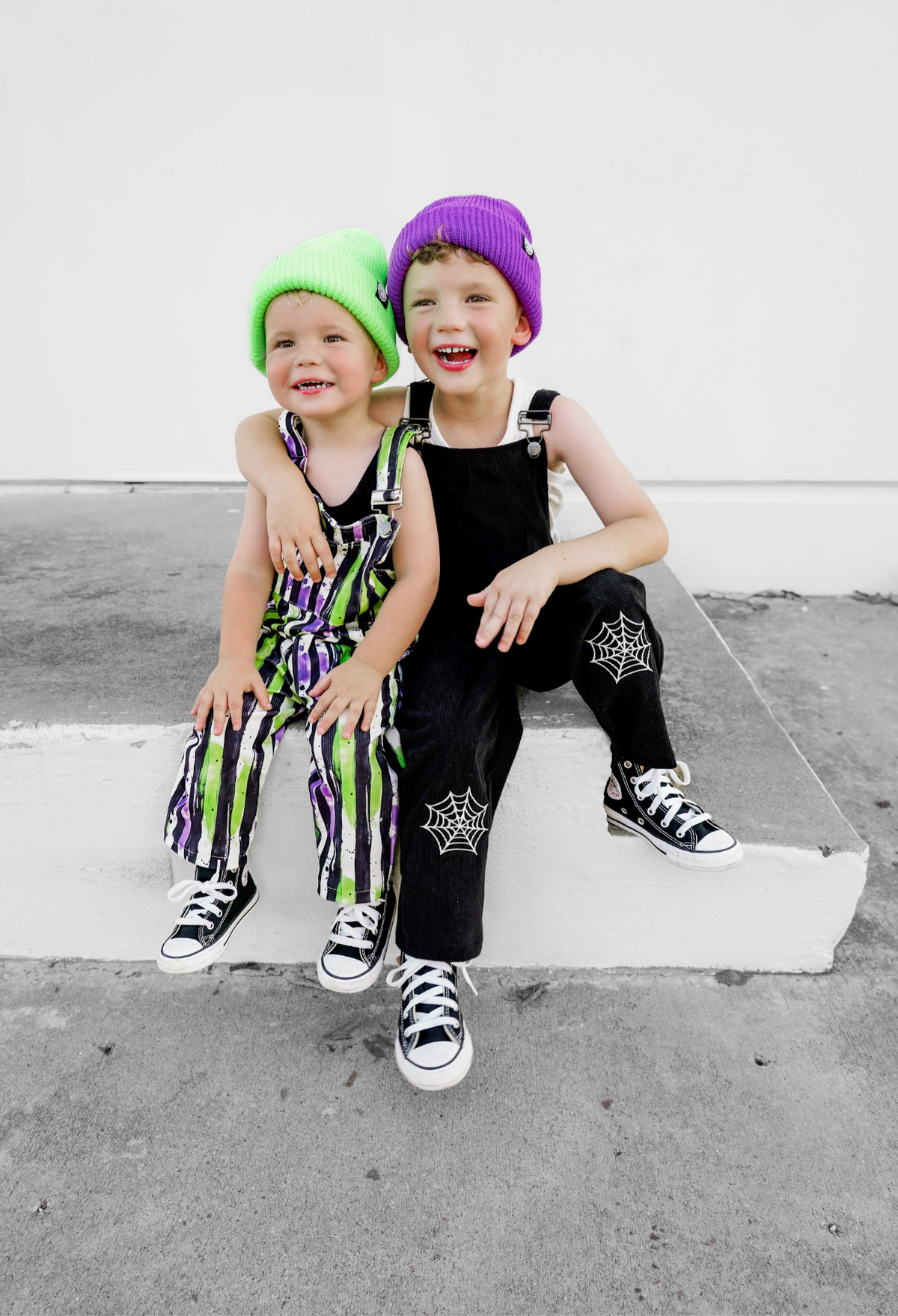 Black overalls with spiderweb patches and front straps worn by a child.