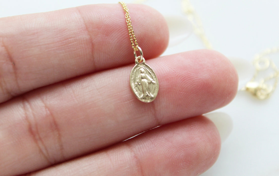 14k gold oval Miraculous pendant on delicate chain, close-up