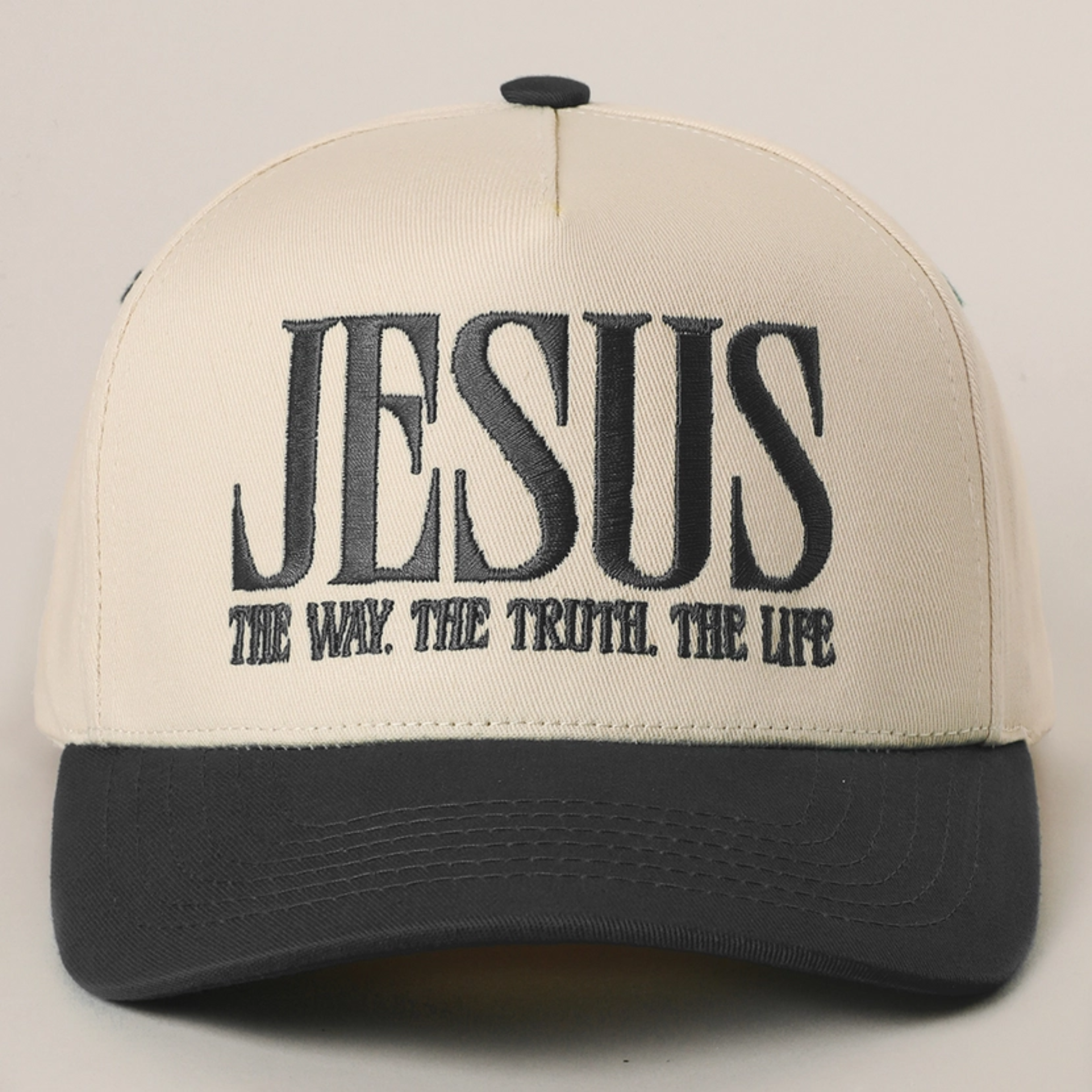Sand baseball cap with black brim and black embroidered “JESUS” slogan on front
