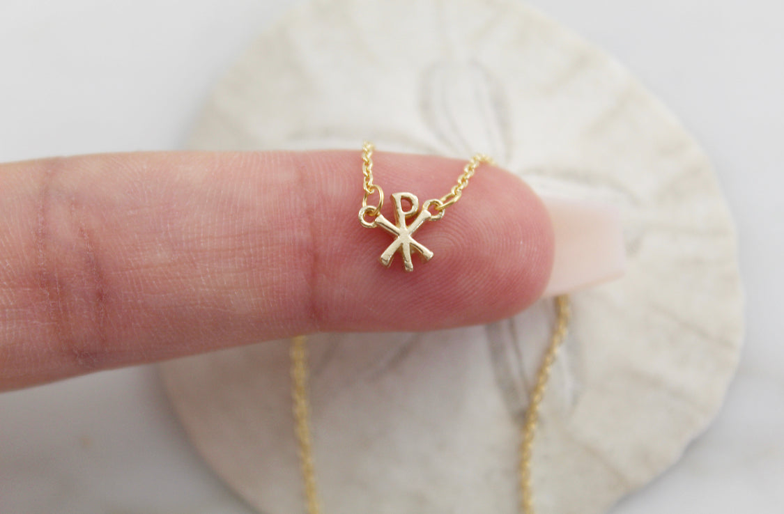 14K gold Chi Rho pendant charm on a delicate chain, palm close-up