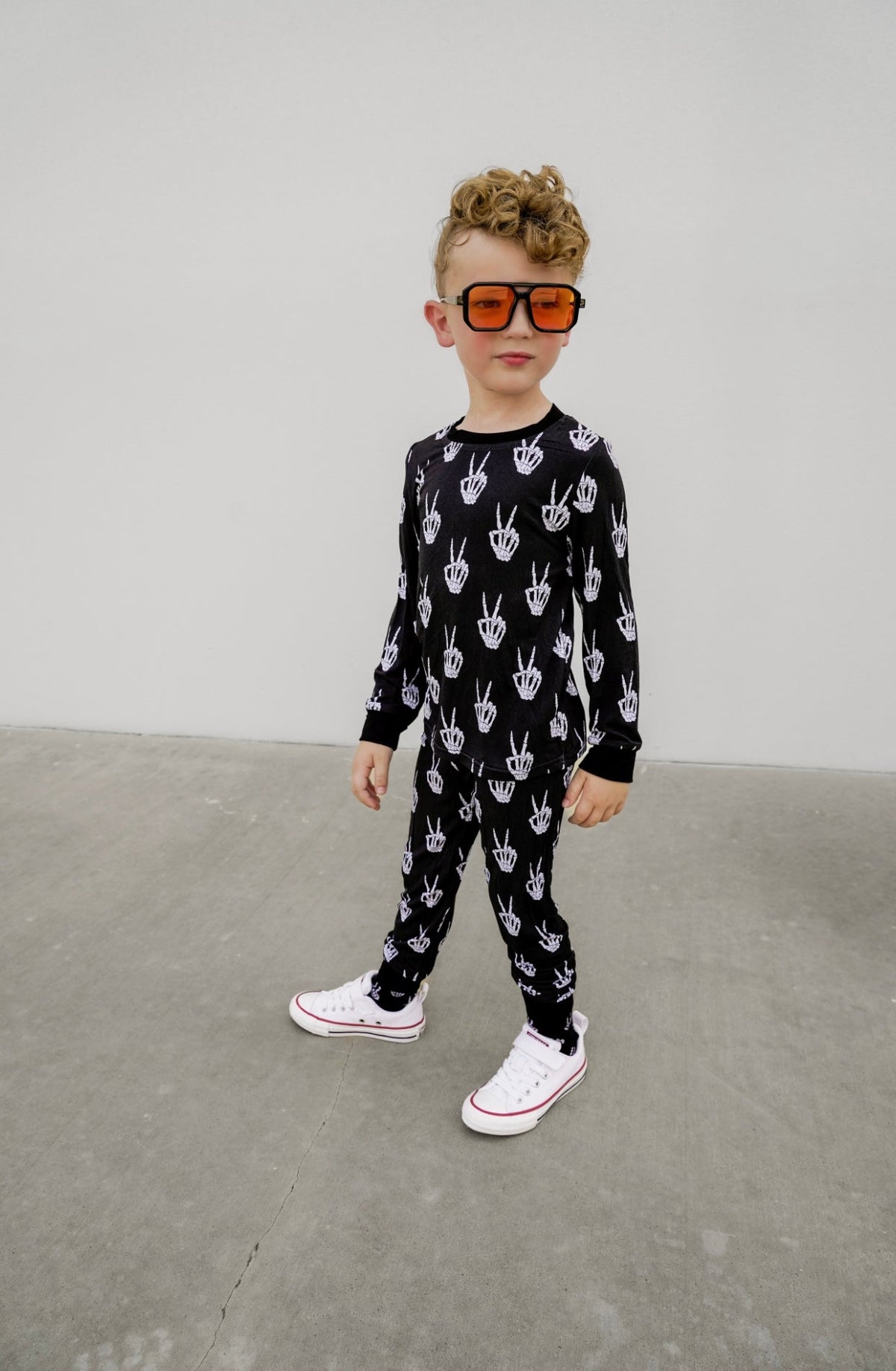 Kids black long-sleeve pajama set with white skeleton-hand print, full length.