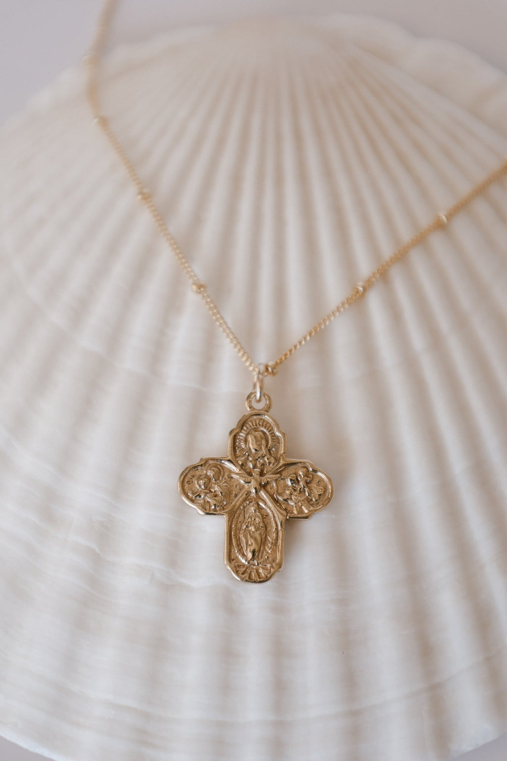 Gold-tone cross pendant necklace with delicate chain, centered front view.