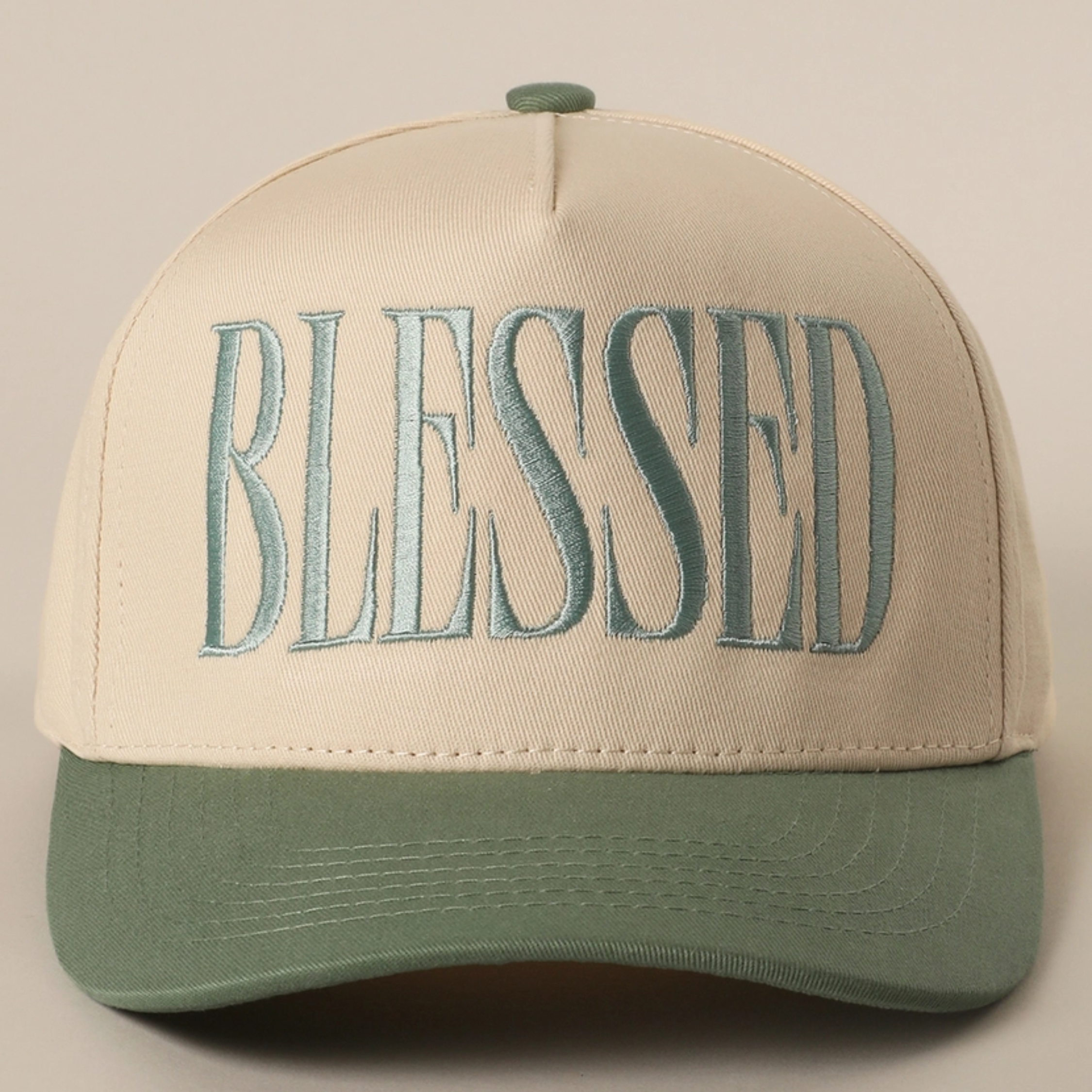 Cream baseball cap with embroidered BLESSED logo and sage green curved brim