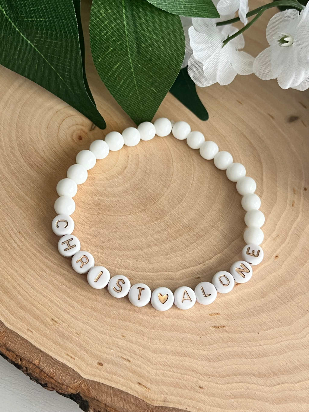 White bead bracelet with round letter beads spelling "CHRIST ALONE"