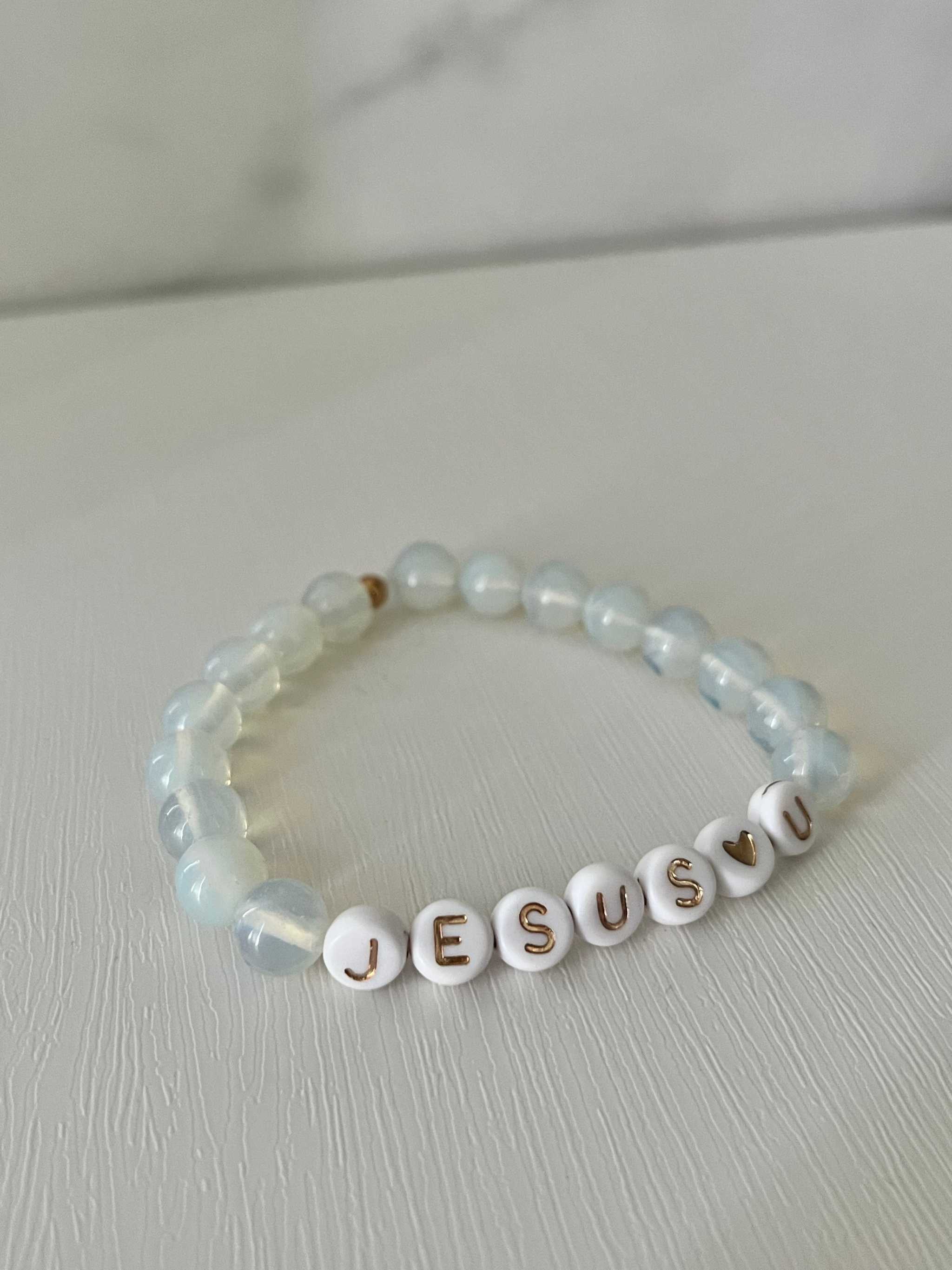 Clear beaded bracelet with white letter beads spelling "JESUS U"