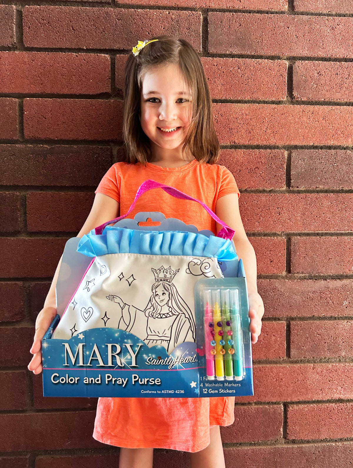 Mary color and pray purse with blue ruffled top, held by a child