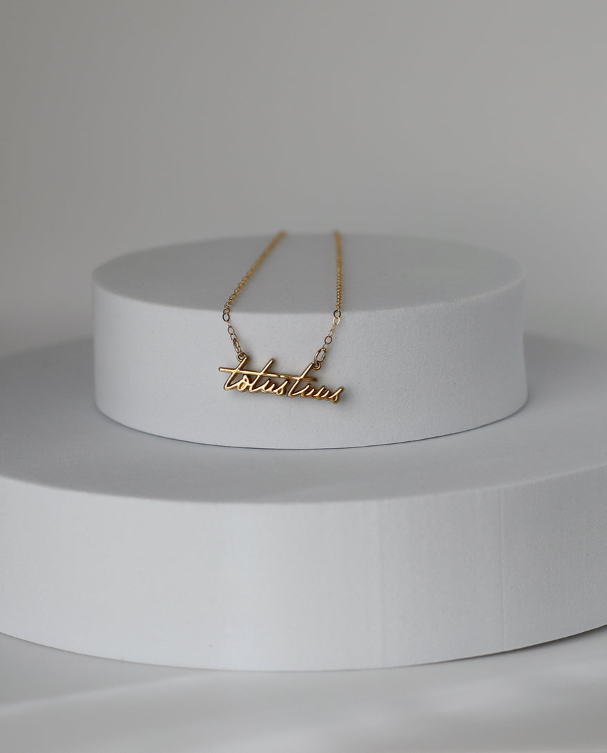Gold-tone script pendant necklace with cross charm on fine chain