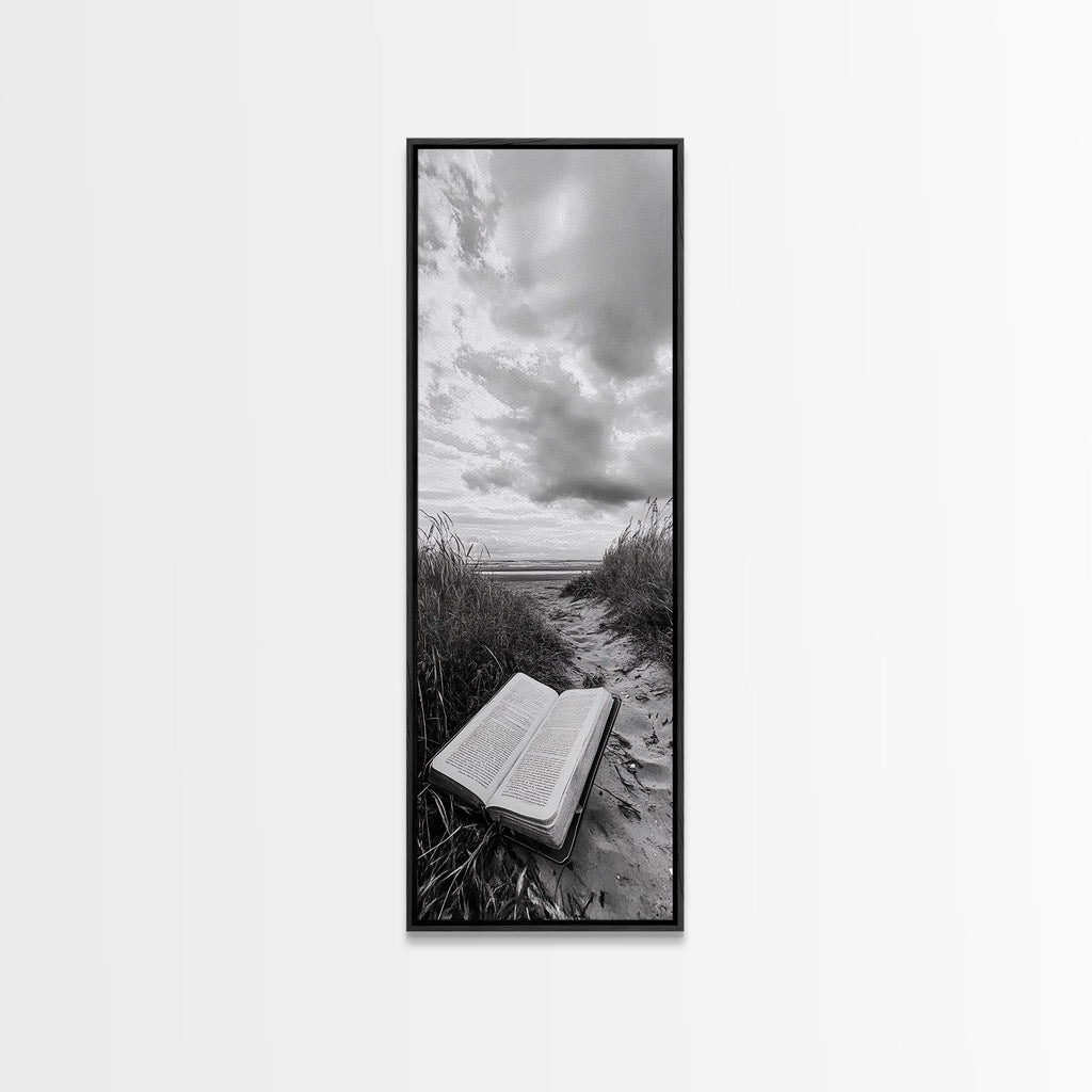 Black framed canvas print of open Bible on a sandy beach path under cloudy sky