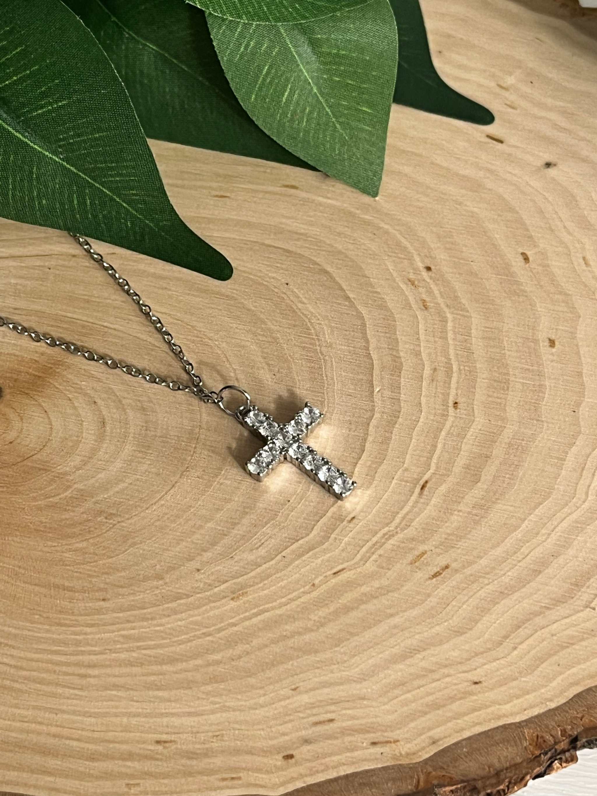 Silver rhinestone cross pendant necklace close-up with chain link visible