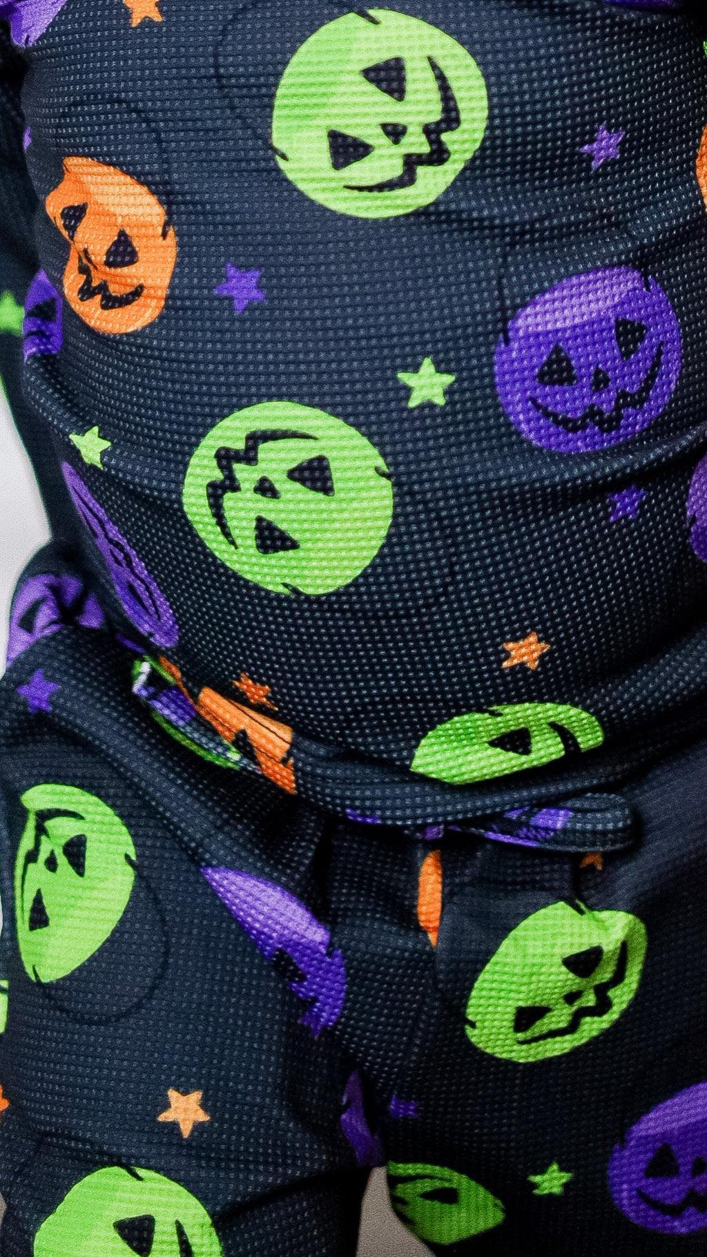 Dark navy waffle-knit fabric with green, orange, purple Halloween face and star pattern