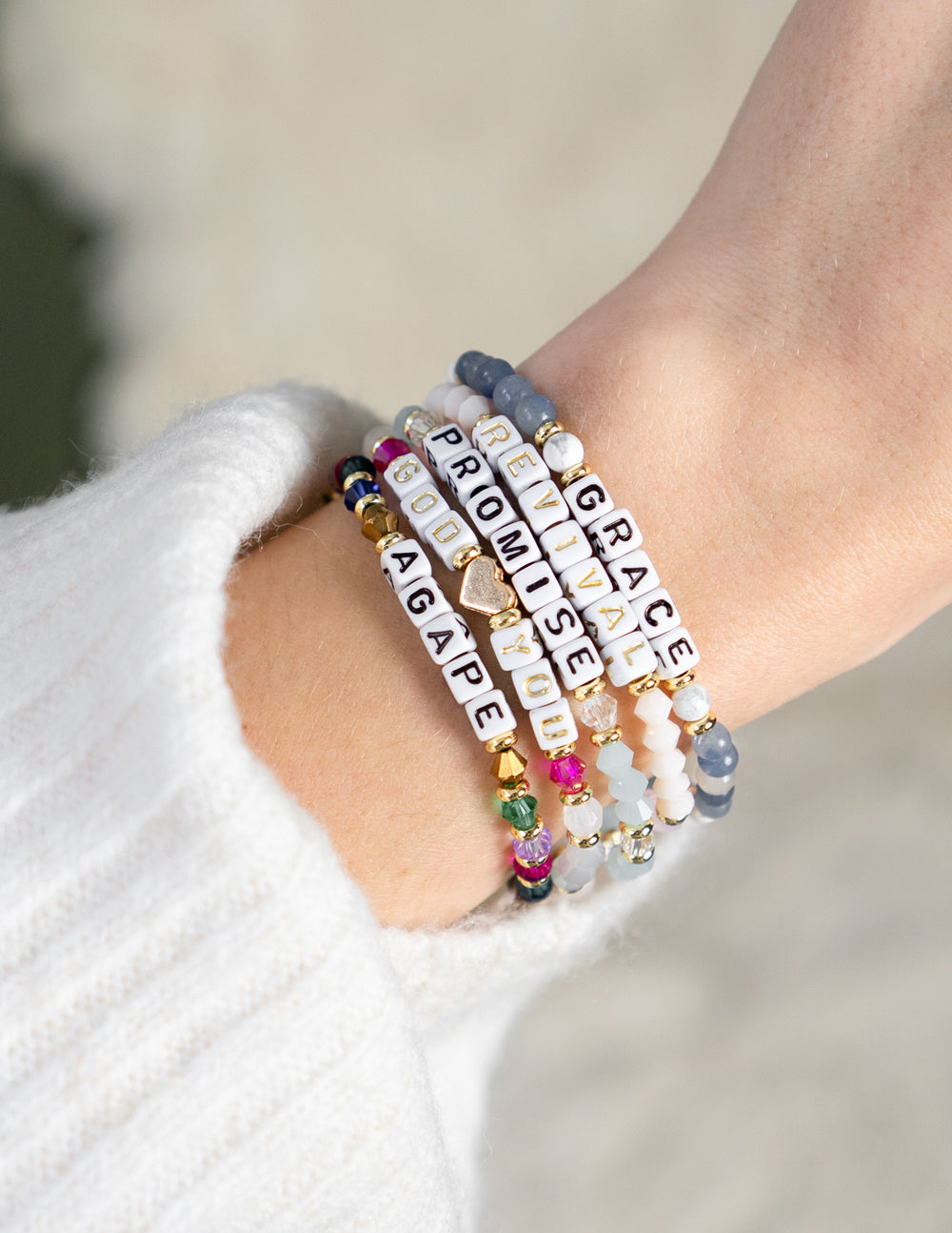 Stacked letter bracelets on wrist, navy and multicolor bead strands with letter beads
