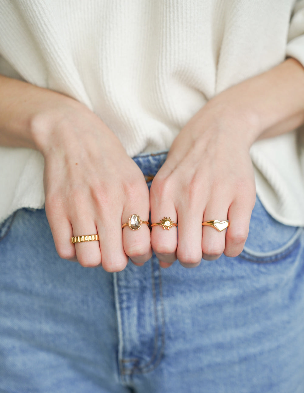 Gold heart signet ring with raised heart face worn on a hand