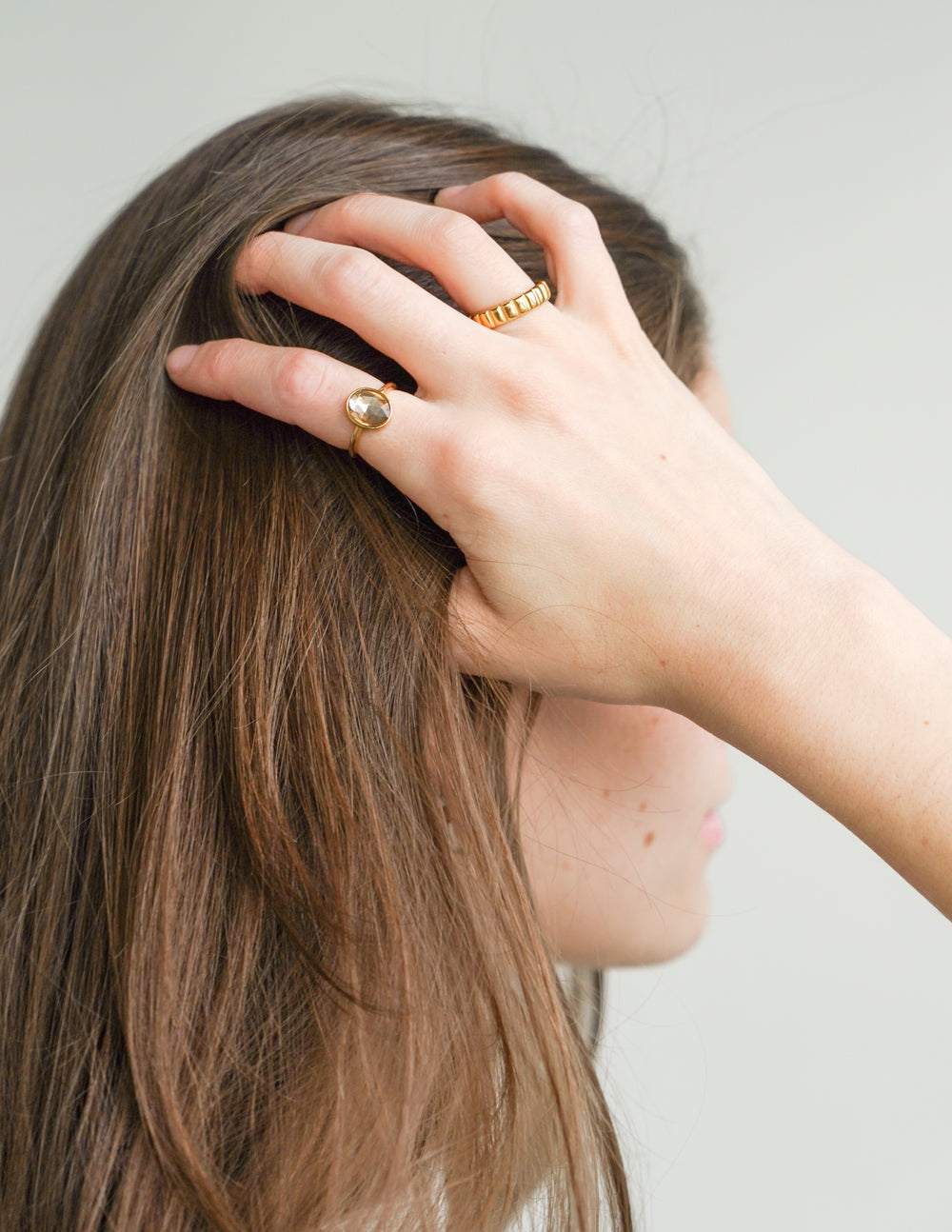 Gold spacer ring on finger, small round charm and ridged band