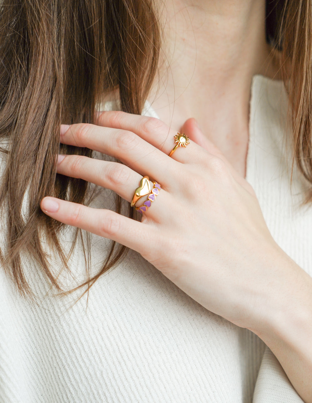 Gold sunburst ring with raised sun charm on hand near face