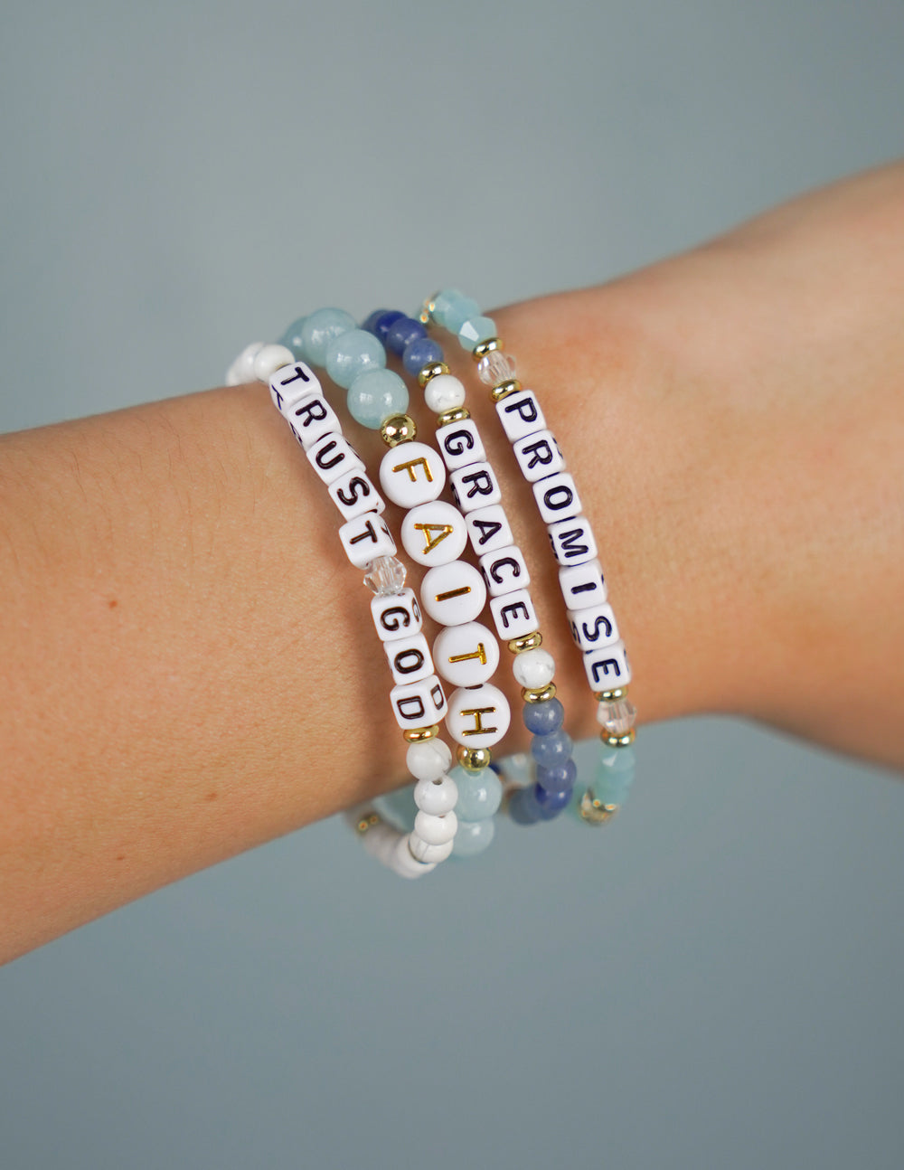Beaded promise letter bracelet on wrist with blue, gold, and white letter beads