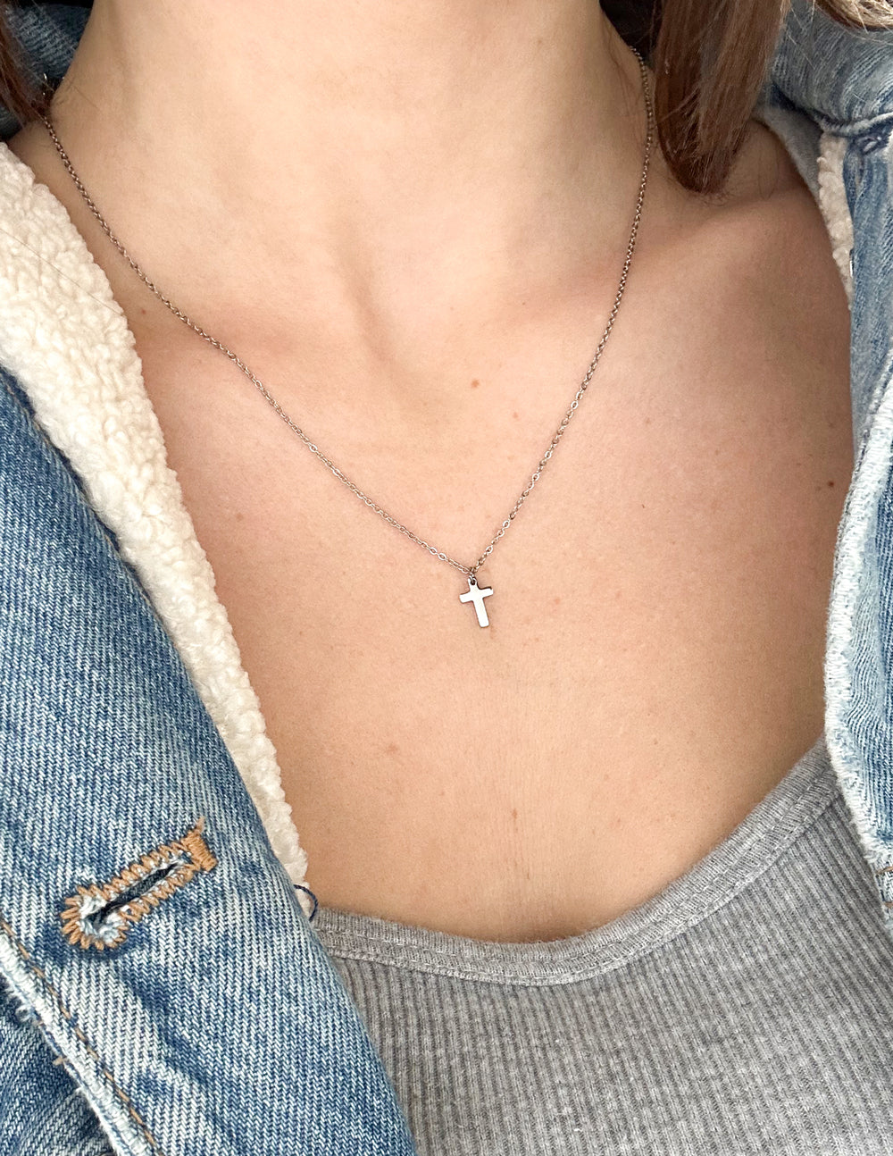 Silver cross pendant necklace worn on chest