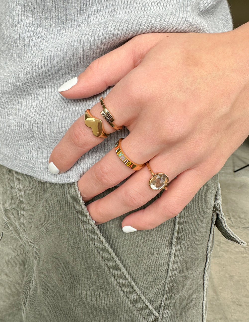 Gold ring with black IMAGO DEI lettering on finger