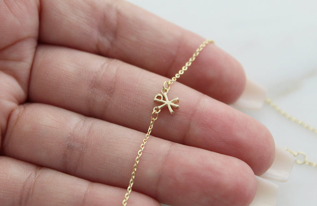 14K gold Chi Rho pendant charm on a delicate chain, close-up