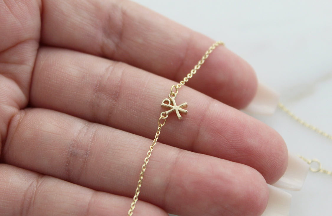 14K gold Chi Rho pendant charm on a delicate chain, close-up