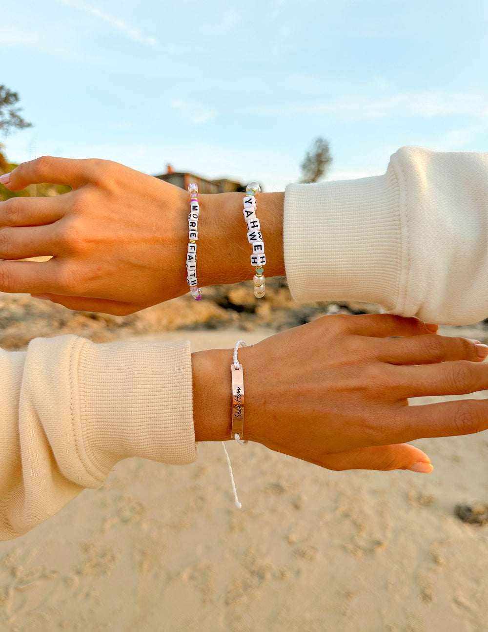 Beaded letter bracelet with gold tone charms and white text tags on wrist