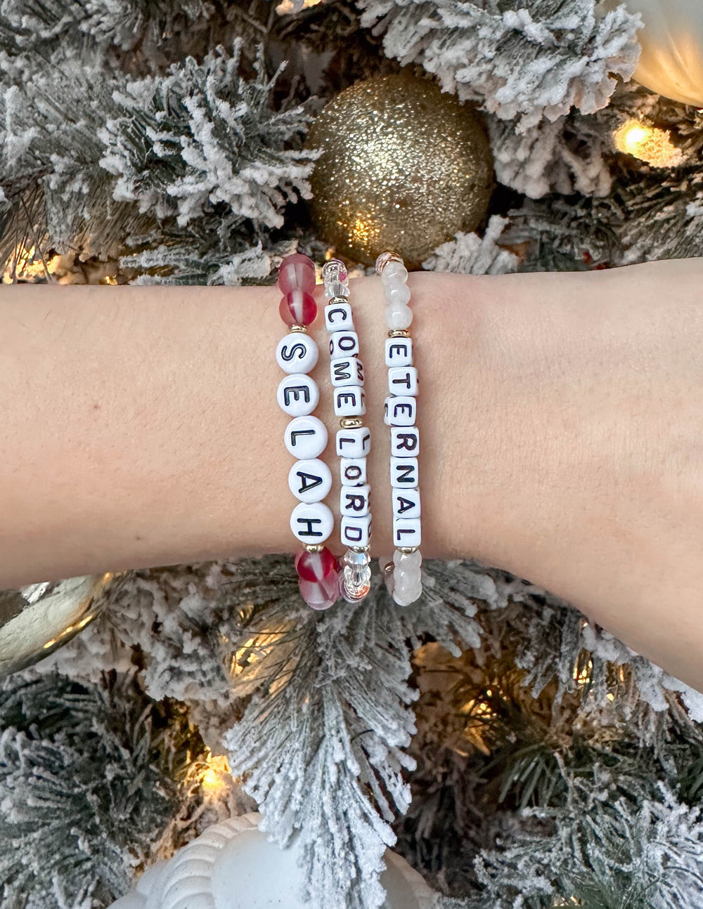 Selah letter bracelet on wrist with red and clear beads and dangling "SELAH" letters
