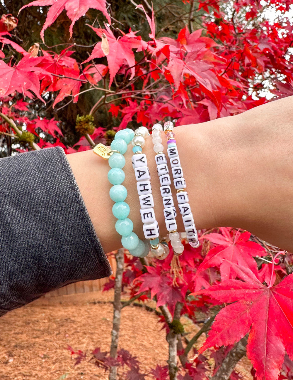 Turquoise beaded letter bracelet with gold spacers, plus white and teal charms.