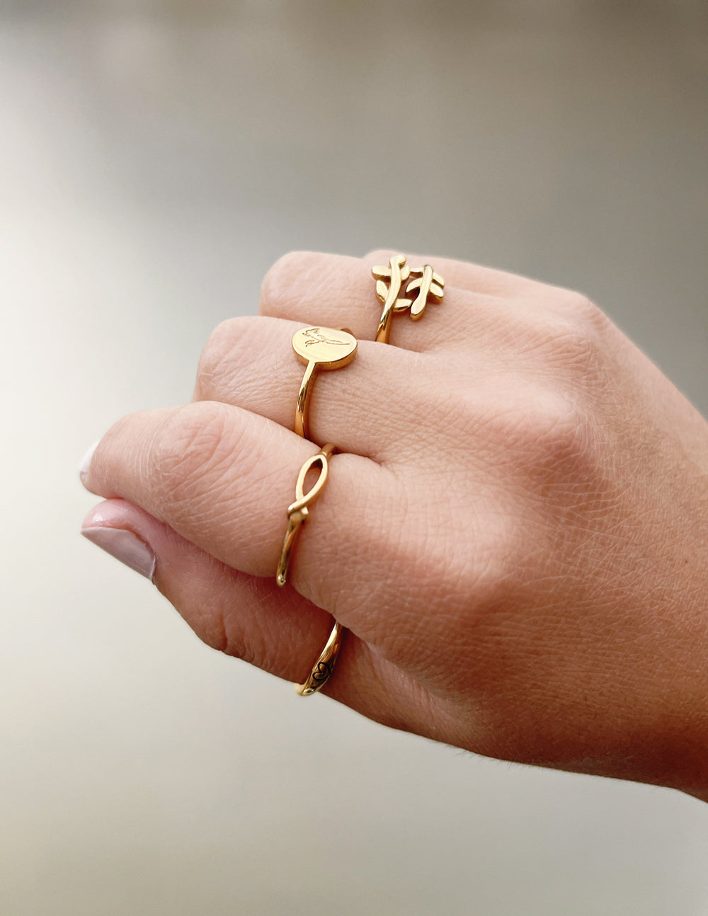 Gold wildflower signet ring on finger, thin band with round floral-engraved top