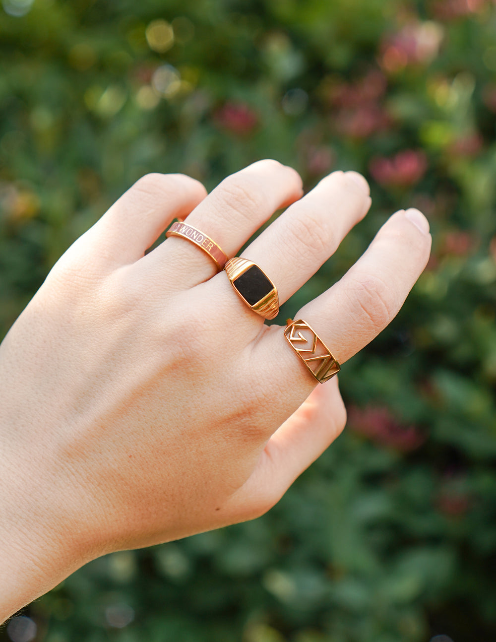 Mauve enamel ring on finger with gold-tone border and geometric cutout