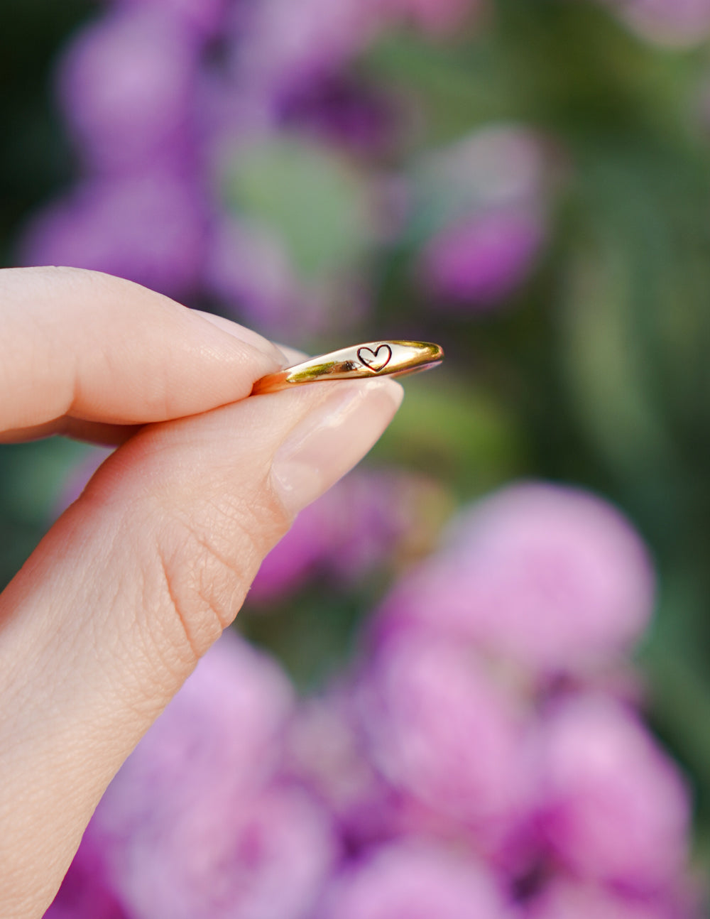 Gold love ring angled view with small heart detail near the edge
